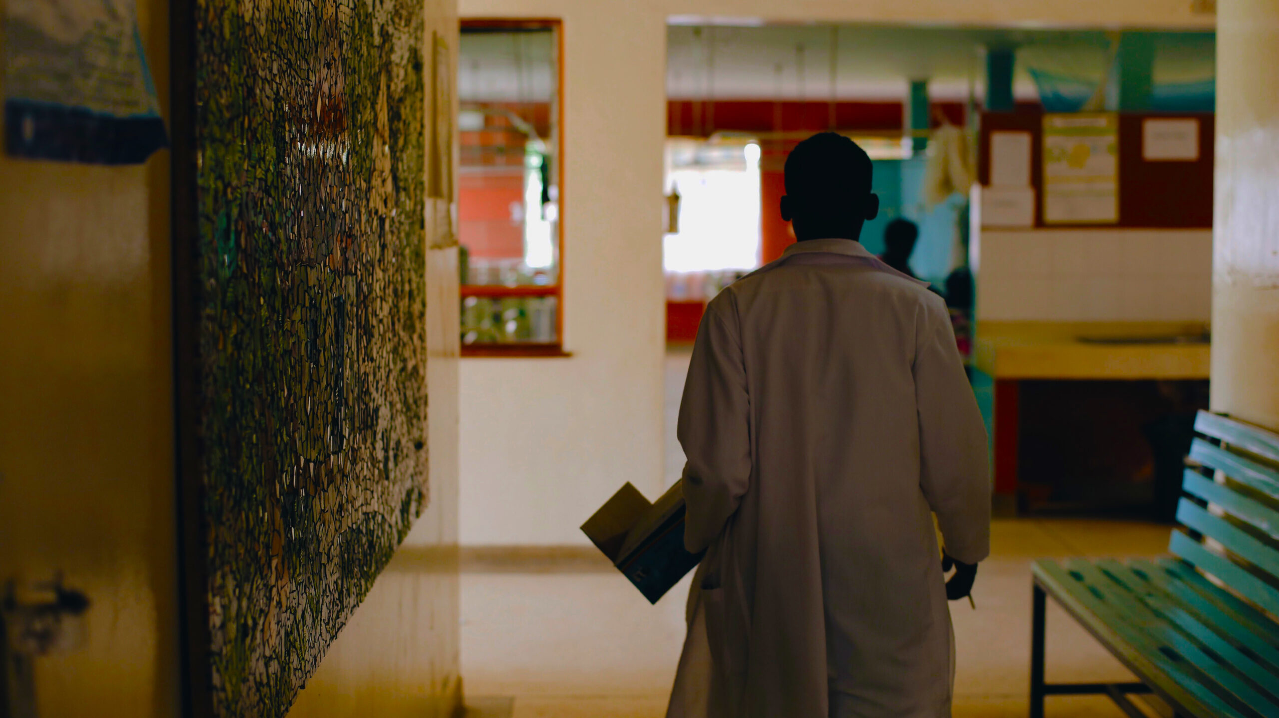 African doctor in white medical gown walking through the hospital lobby in village in Africa.